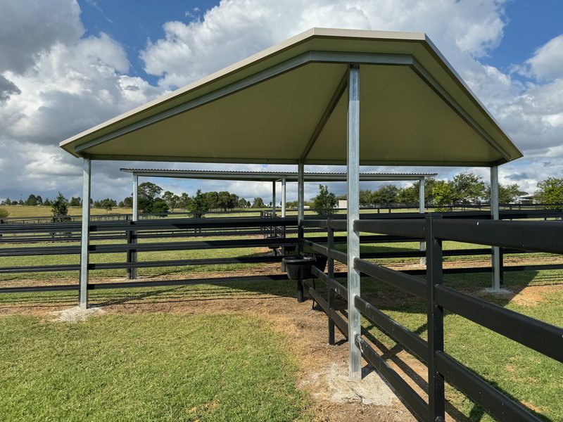Round steel shelter with hipped roof beside black post-and-rail fencing